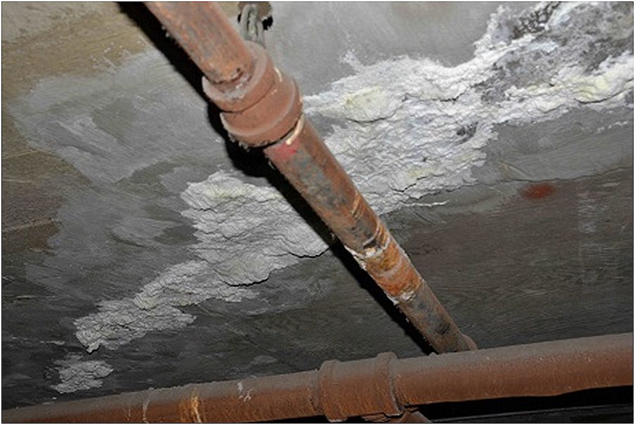 Rusty pipes are attached to a ceiling with visible water damage. The ceiling shows areas of white staining and peeling, indicating possible leaks or mold growth. The pipes and ceiling appear aged and in need of repair. Waterproofing Company | Basement Leak Repair | City Wide Group | Professional waterproofing company and basement leak repair in Toronto since 1961. | https://www.citywidegroup.com | +1 416-283-5500