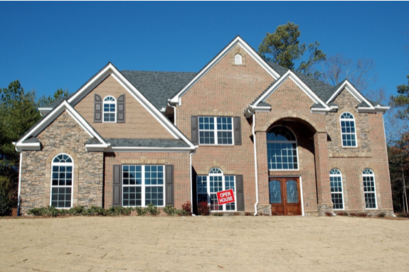 A large two-story brick house with multiple windows and a prominent arched entrance. A red Open House sign is placed in front of the building. The background features a few trees and a clear blue sky. Waterproofing Company | Basement Leak Repair | City Wide Group | Professional waterproofing company and basement leak repair in Toronto since 1961. | https://www.citywidegroup.com | +1 416-283-5500
